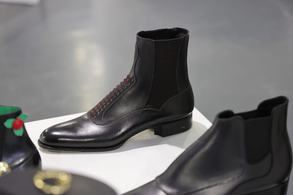 A black leather ankle boot with burgundy laces and a textured side panel.