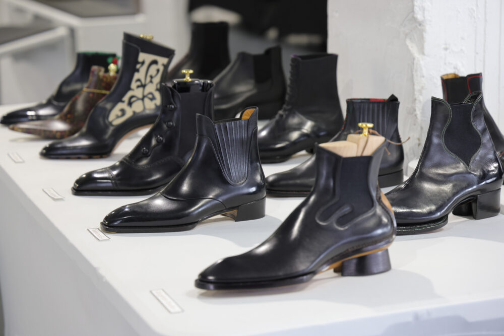 A collection of black leather boots with various styles and designs, displayed on a white surface.