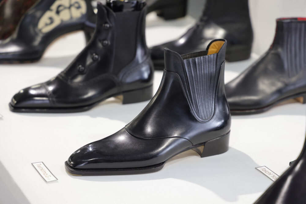 A sleek black leather ankle boot with a pointed toe and ribbed detailing on the sides.