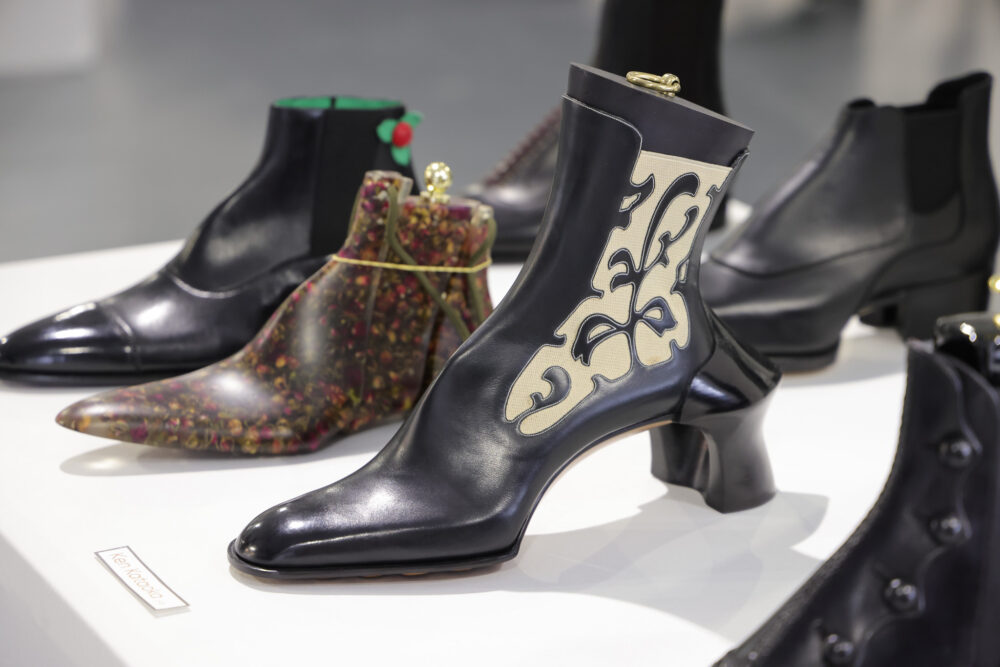 A black leather ankle boot with a decorative cream design and a chunky heel.