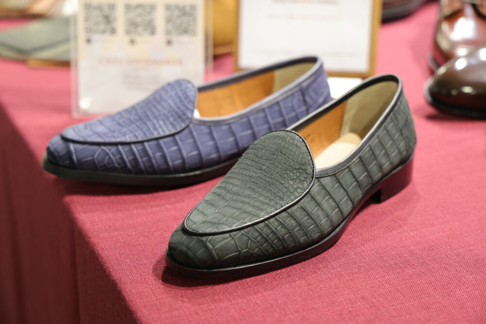 A pair of textured loafers, one in dark blue and the other in dark green, made from crocodile leather.