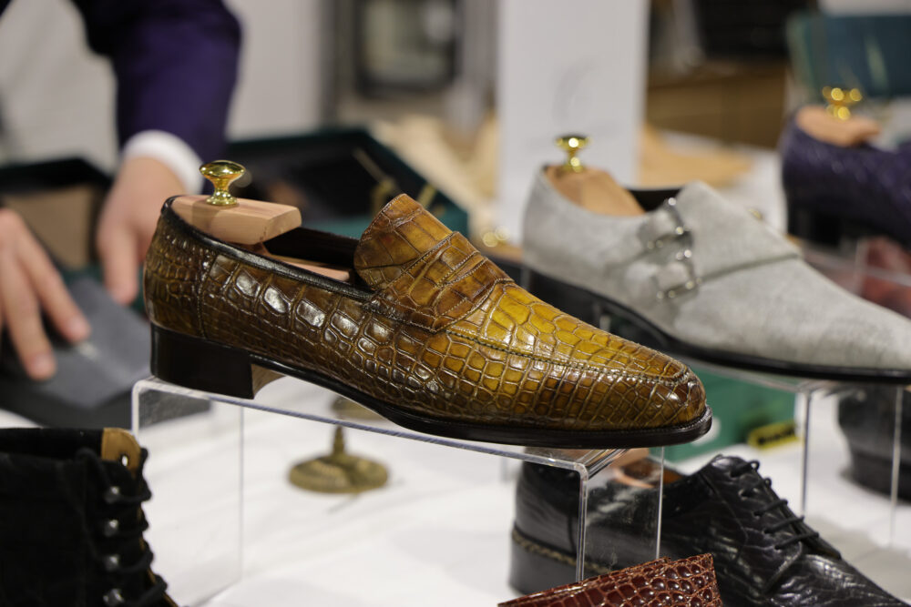 A brown and yellow crocodile leather loafer with a wooden shoe tree.