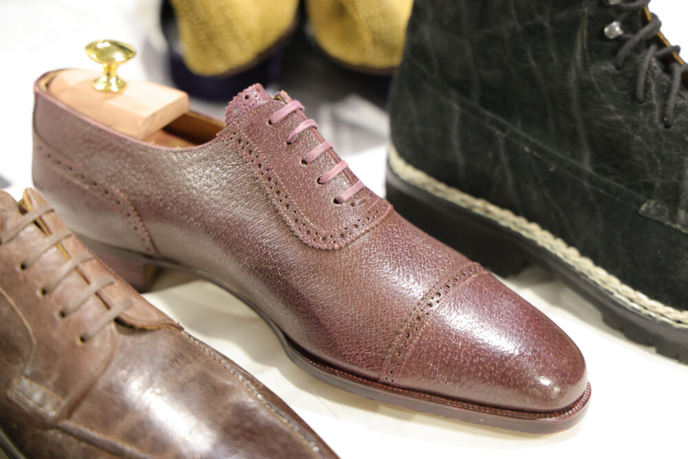 A burgundy leather dress shoe with a cap toe and decorative broguing.
