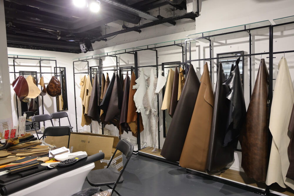 A variety of leather hides in different colors, including brown, black, and cream, are displayed on racks.