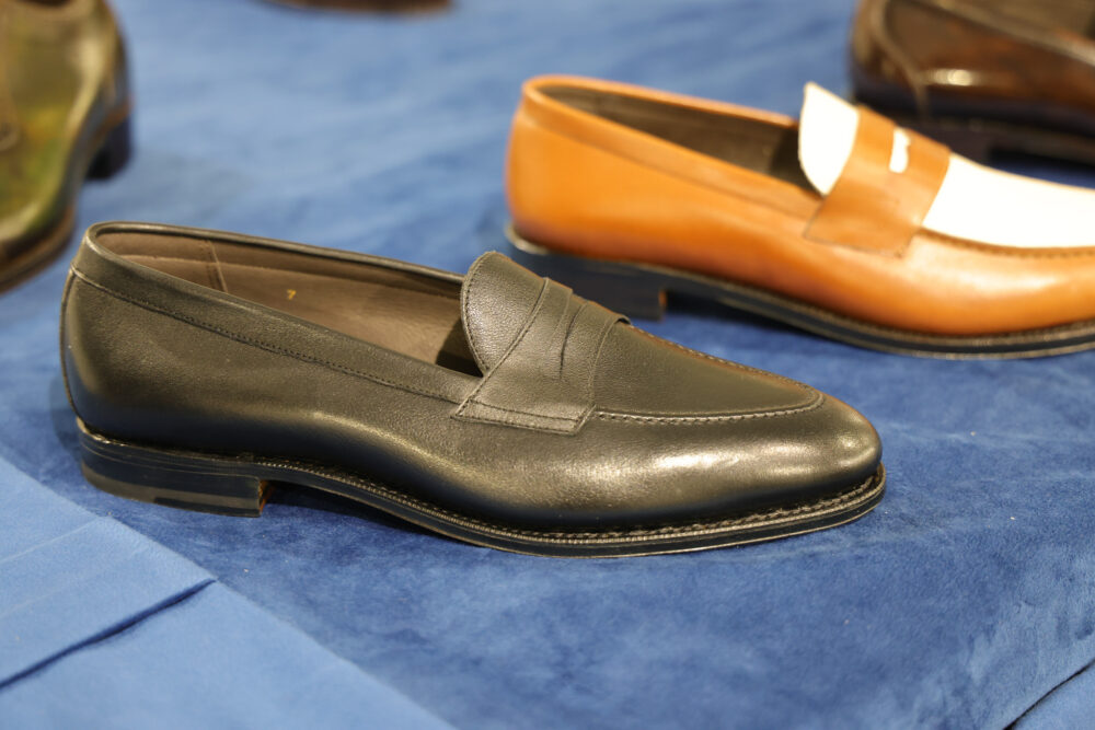 A black leather loafer shoe with a smooth finish and a stitched detail on the front.
