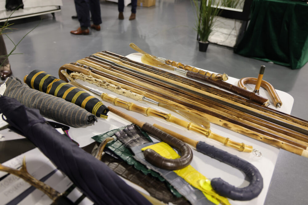 A collection of various canes and umbrellas, featuring materials like wood and fabric in colors such as black, yellow, and brown.