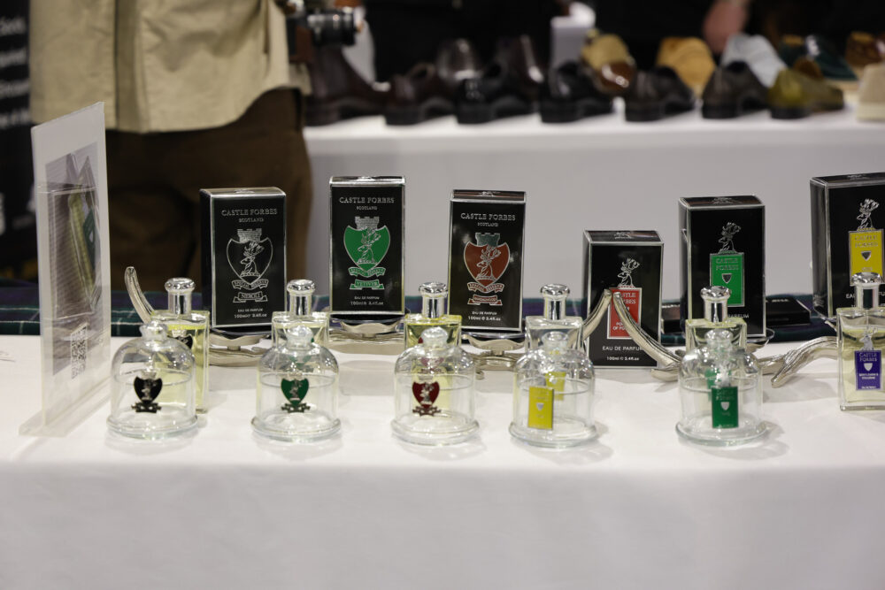 A display of Castle Forbes perfume bottles in clear glass, each with a colored label, alongside matching black and colored boxes.