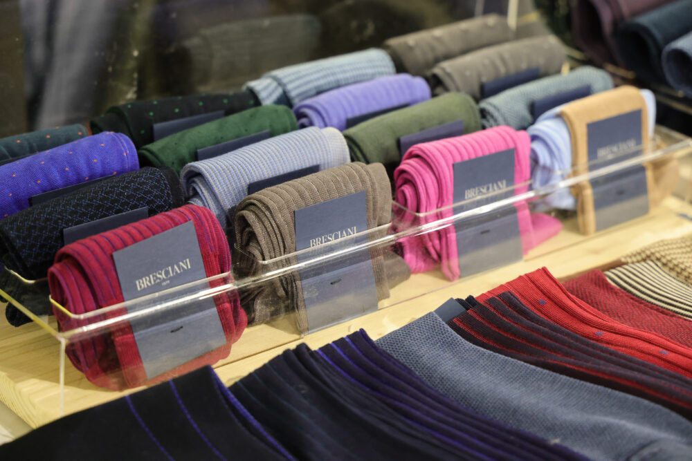 A variety of rolled socks in different colors, including blue, green, pink, and burgundy, displayed with labels.