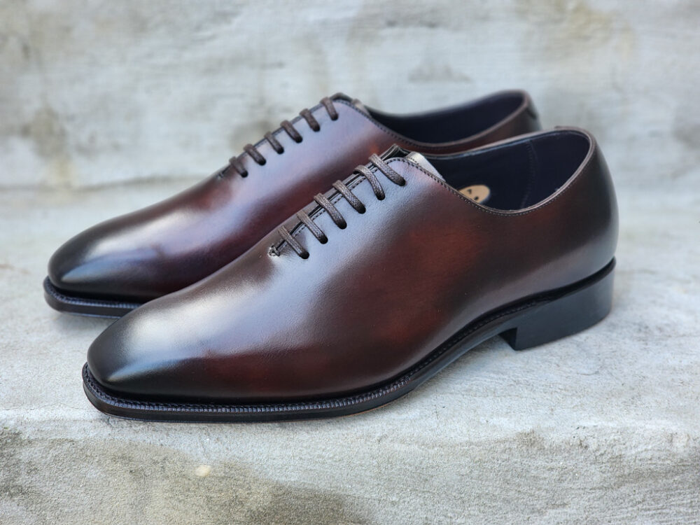 A pair of polished brown leather dress shoes with a rounded toe and laces.