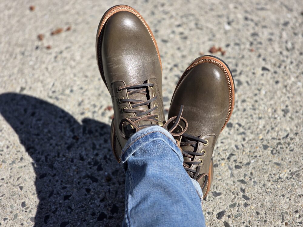 Brown leather boots with tan soles, worn with blue jeans.