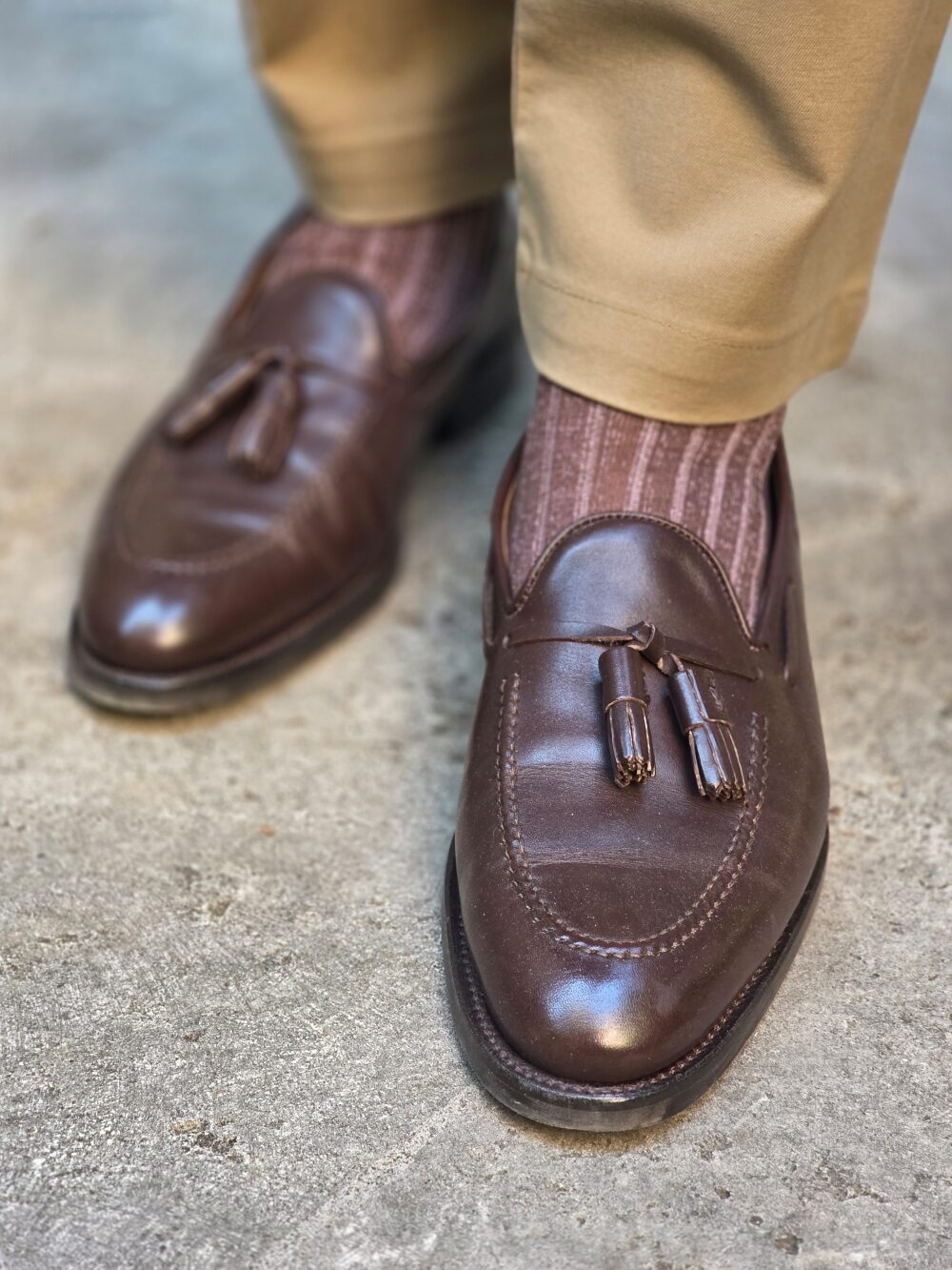 Brown leather loafers with tassels and ribbed brown socks.