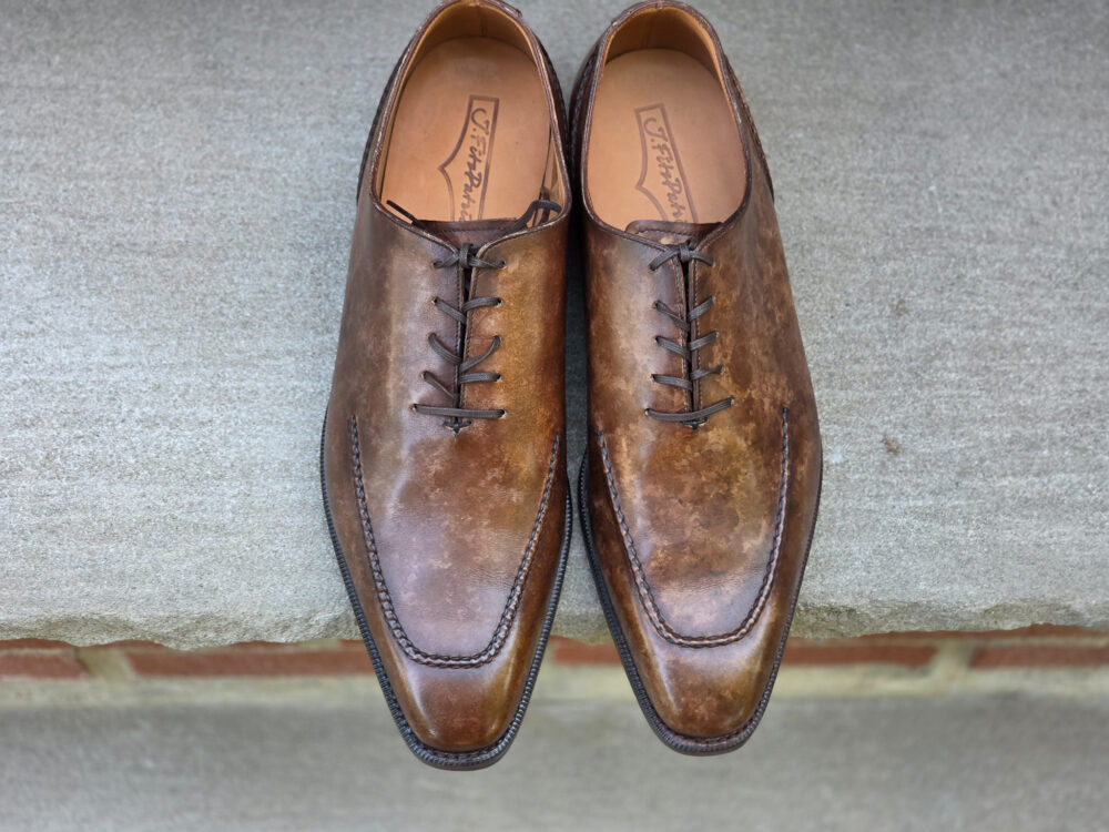 A pair of brown leather dress shoes with a pointed toe and lace-up design.