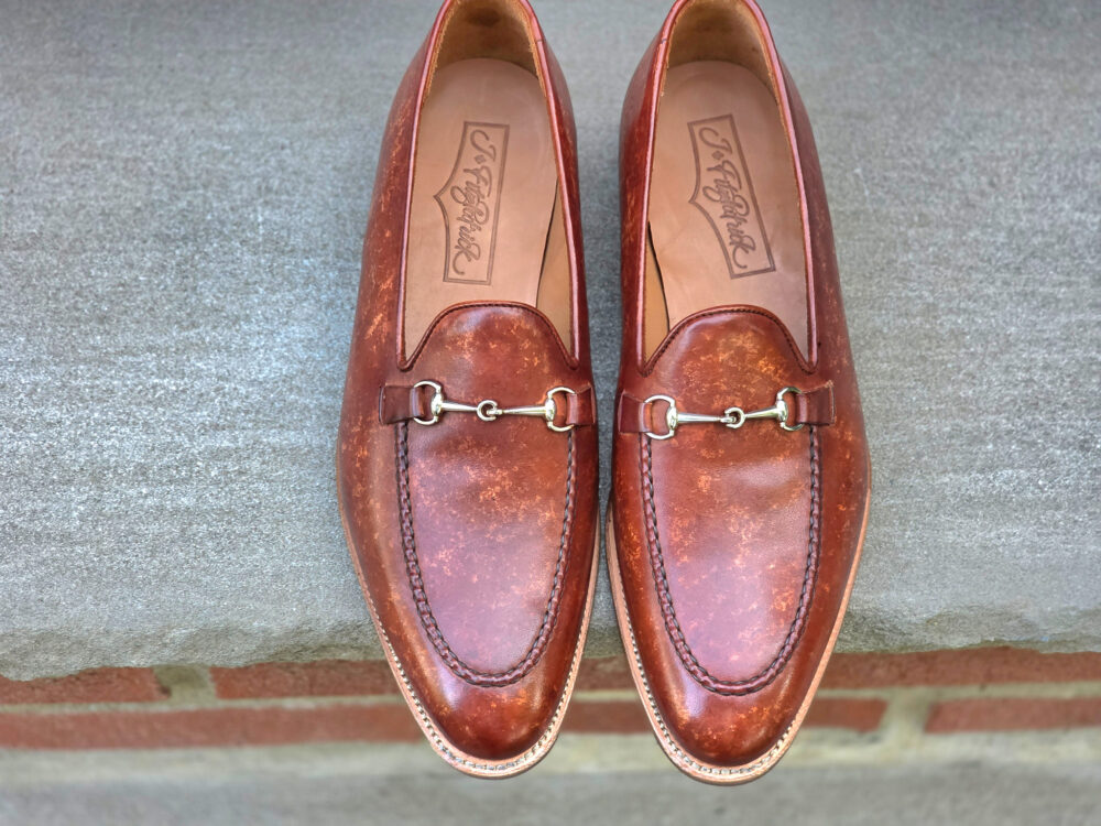 Brown leather loafers with a decorative silver bit detail on the front.