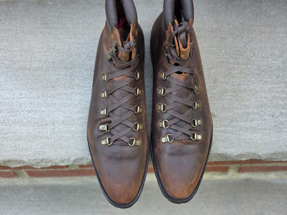 A pair of brown leather hiking boots with metal eyelets and laces.