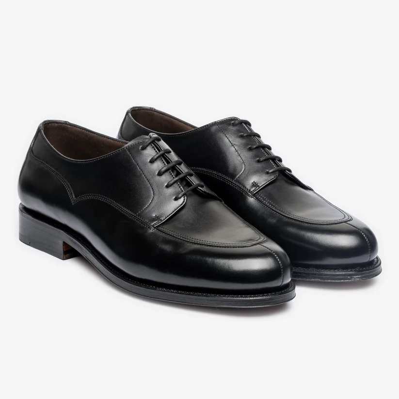 A pair of polished black leather dress shoes with laces and a rounded toe.
