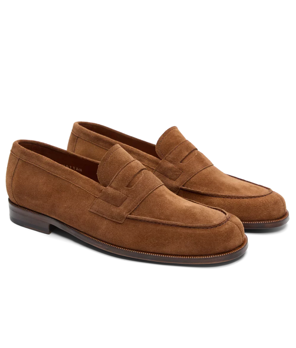 Brown suede loafers with a decorative strap across the upper.