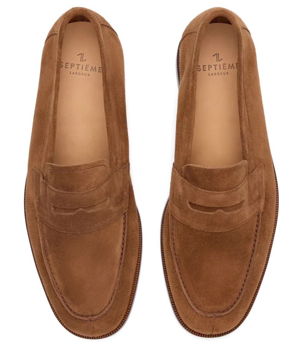 Brown suede loafers with a slip-on design and a decorative strap.