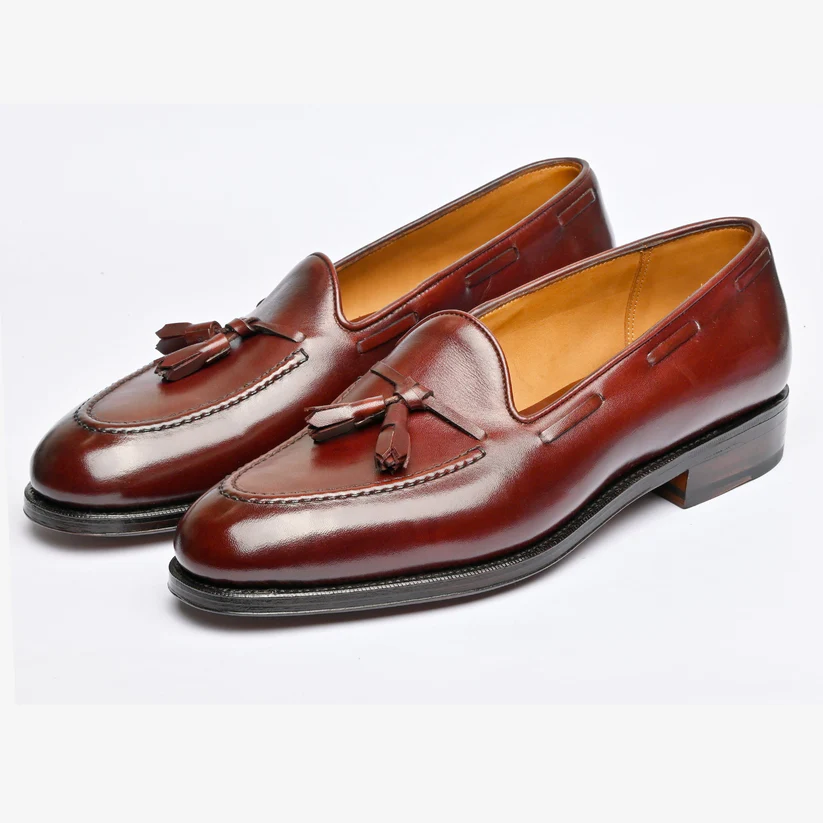 Brown leather loafers with tassels and a sleek design.