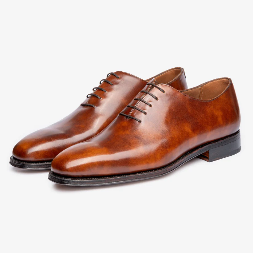 A pair of polished brown leather dress shoes with laces.