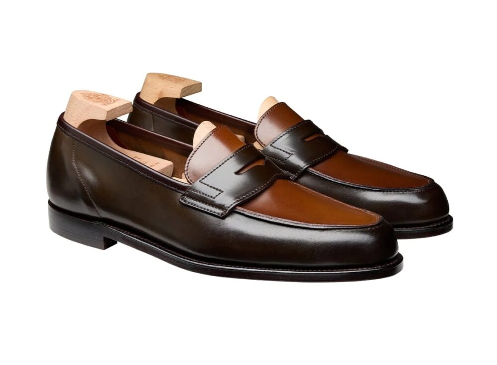 A pair of brown leather loafers with a darker brown accent and wooden shoe trees inside.