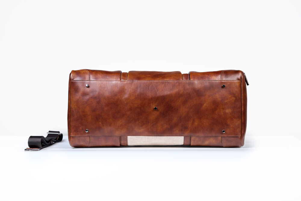 A brown leather bag with a textured surface and a detachable black strap.
