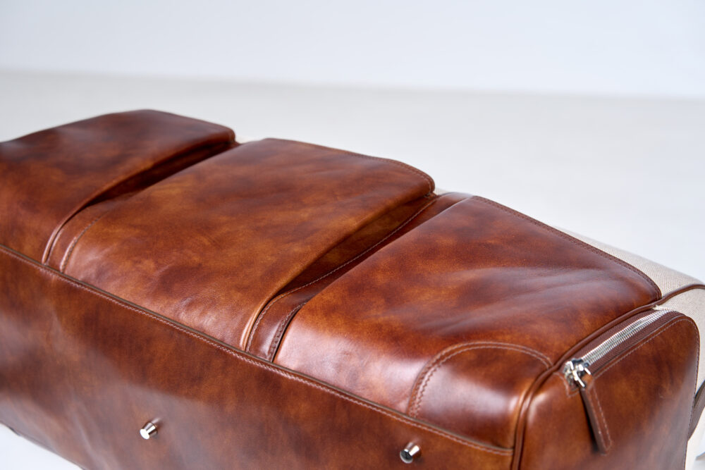 A brown leather bag with a smooth finish and silver zipper detail.