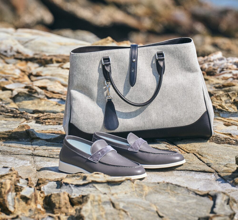 A gray and black tote bag sits beside a pair of gray loafers with white soles.
