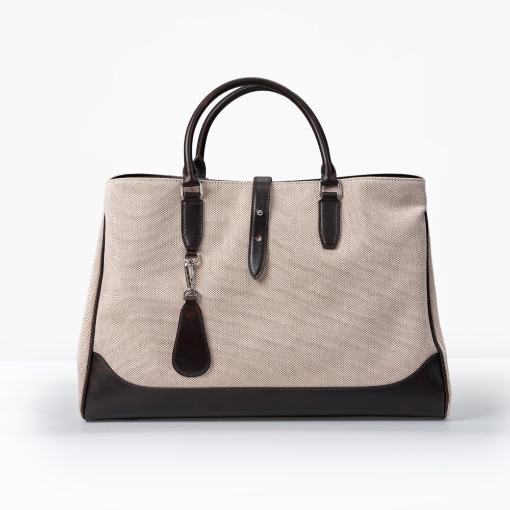 A beige canvas handbag with dark brown leather trim and handles.