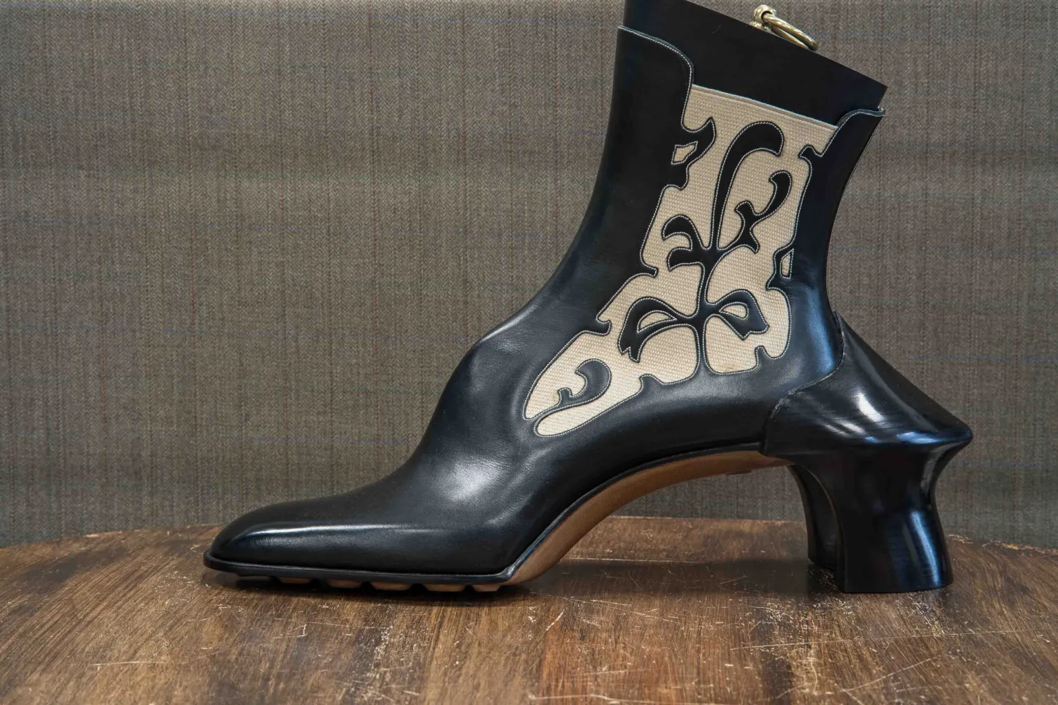 A black and cream ankle boot with a unique floral design and a sculptural heel.