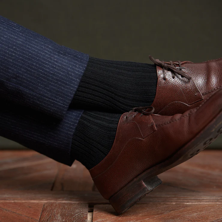 Brown leather shoes, black ribbed socks, and navy pinstriped trousers.