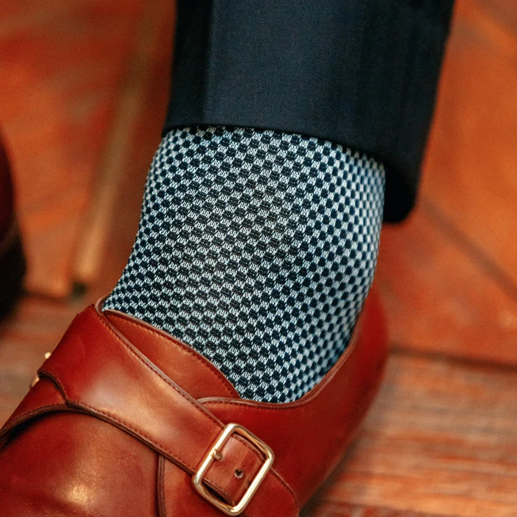 A brown leather shoe is paired with a blue and white checkered sock.