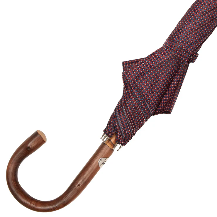 A folded umbrella with a patterned fabric in red and blue, featuring a wooden handle.