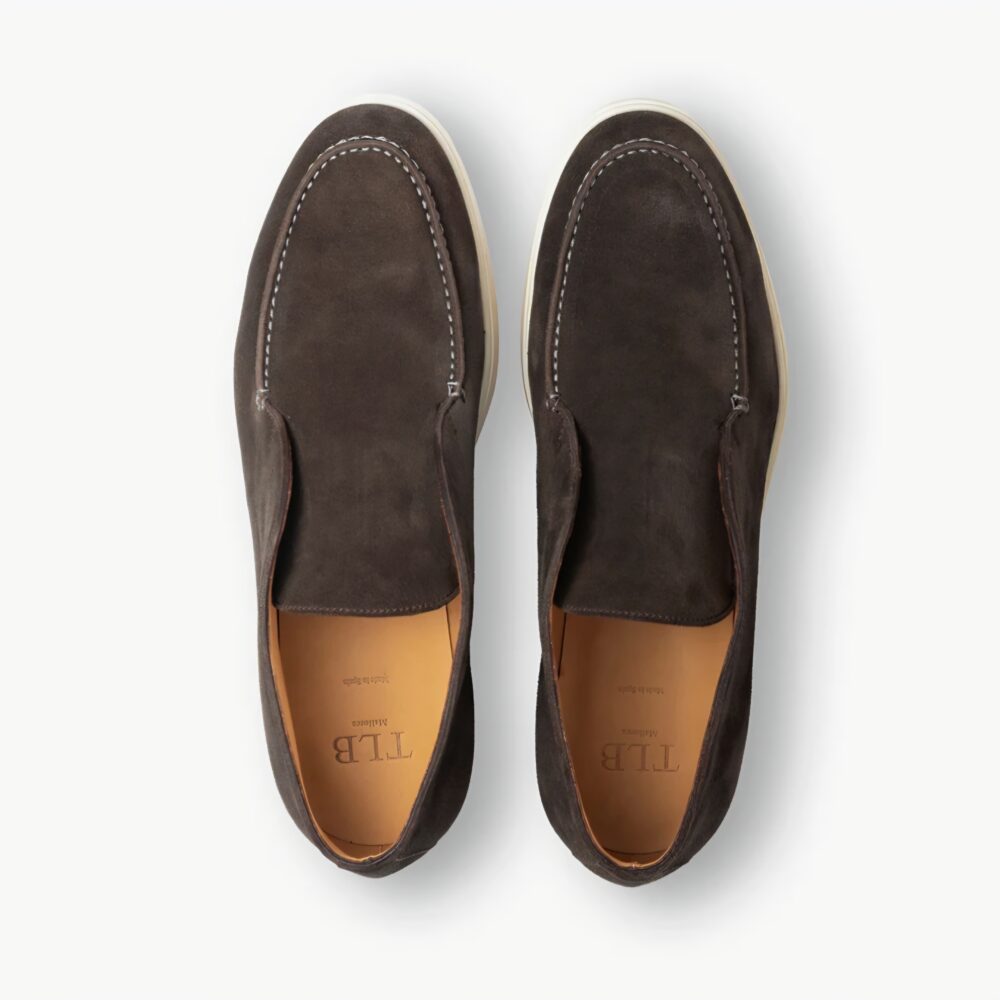 A pair of dark brown suede TLB Mallorca Laceless Ankle Boots with white stitching and a light-colored sole.