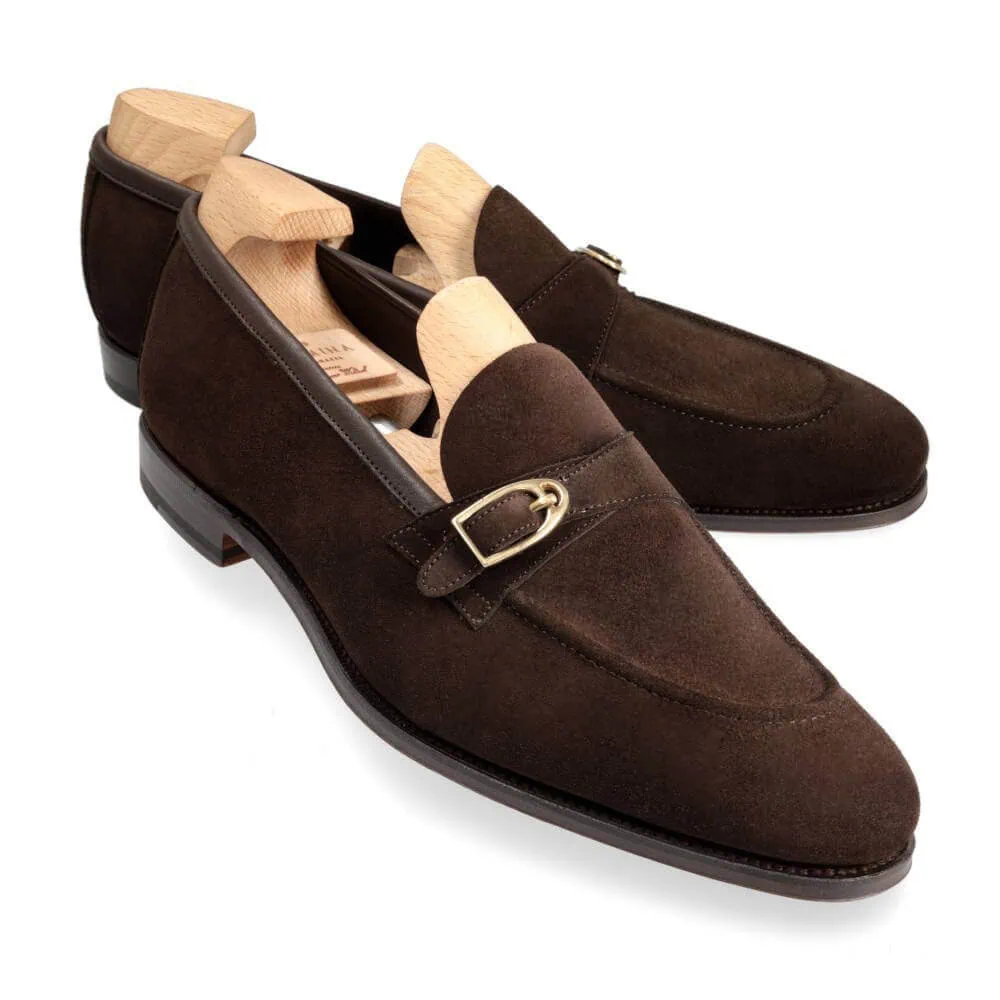 Brown suede loafers with a gold buckle detail and wooden shoe trees inside.