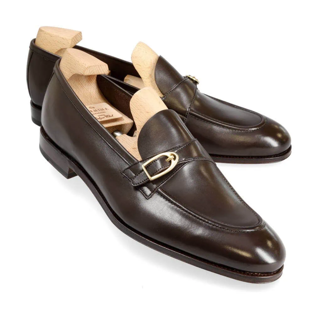 A pair of dark brown leather loafers with wooden shoe trees inserted.