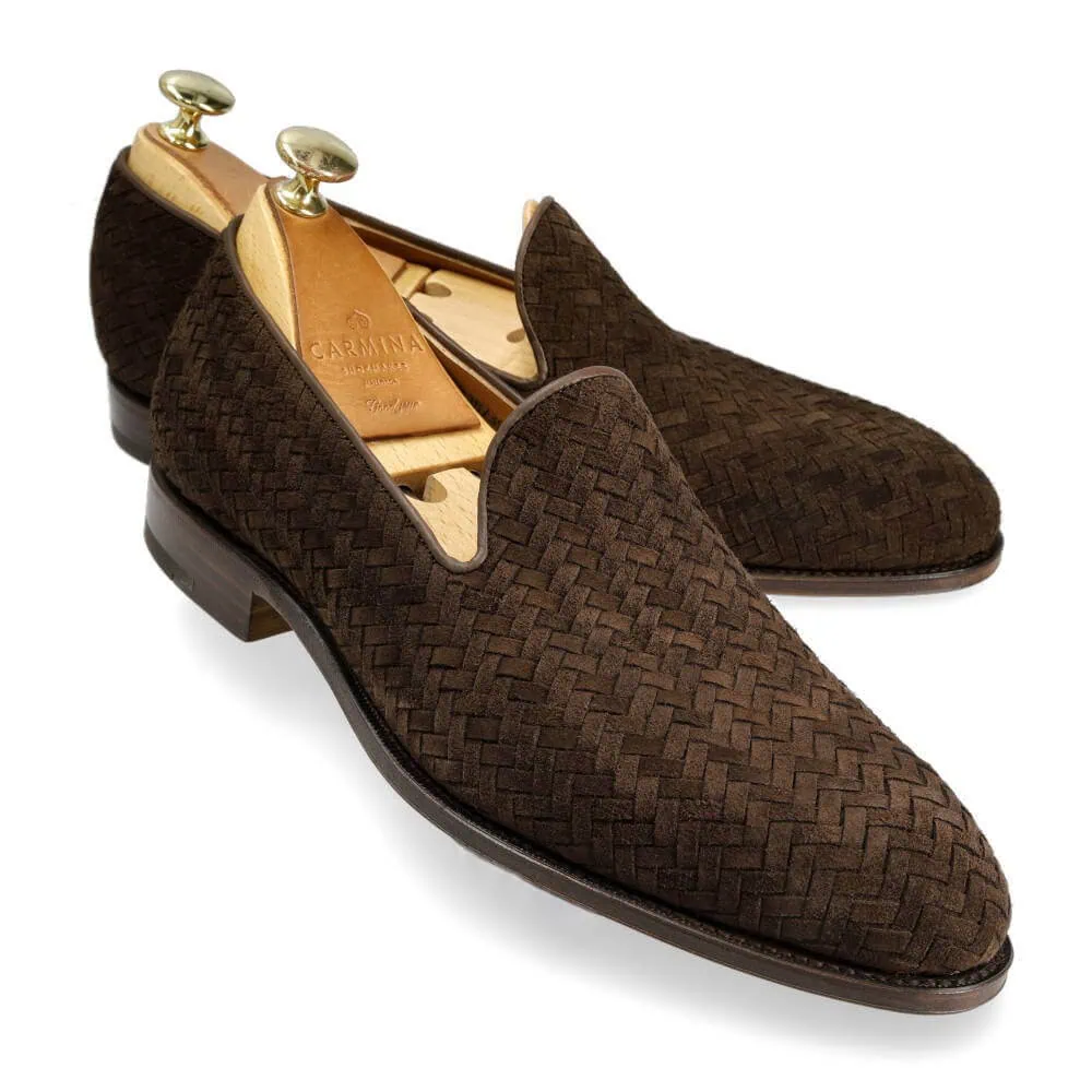 A pair of dark brown woven slip-on shoes with wooden shoe trees inserted.