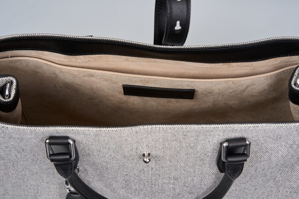 A gray and black handbag with a spacious interior and leather accents.