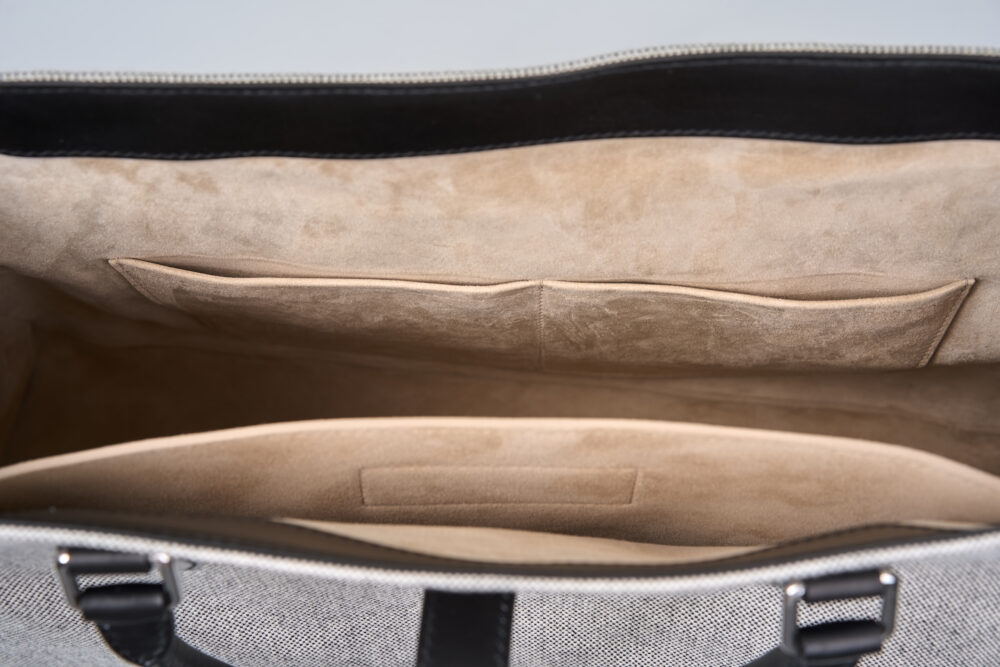 An open gray bag with a soft beige interior featuring two pockets.
