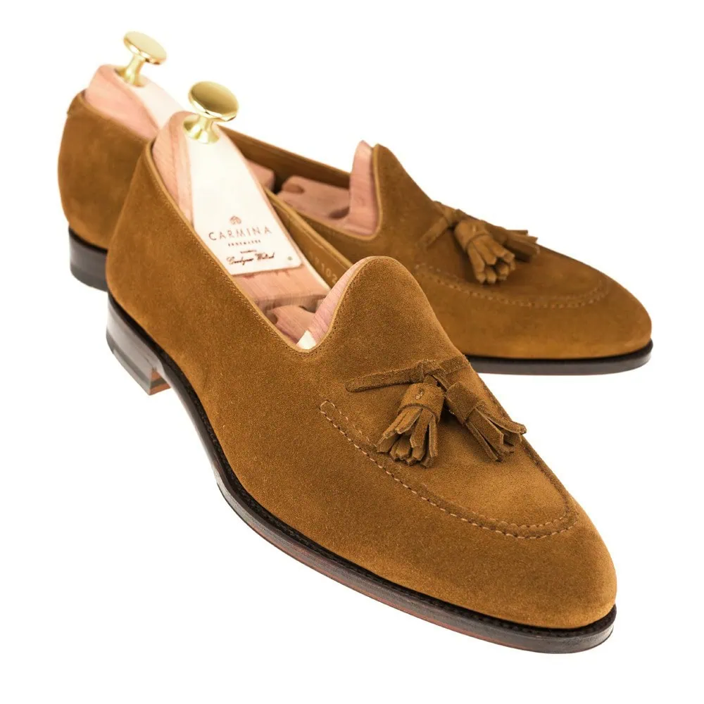Brown suede loafers with tassels and a black sole.
