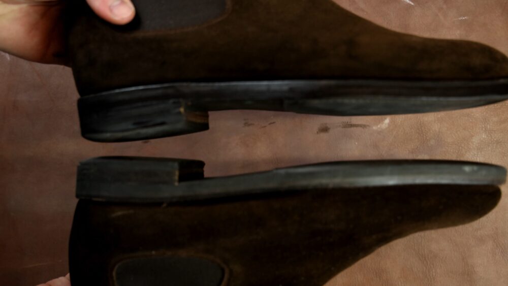 A pair of brown suede boots with visible wear on the soles.