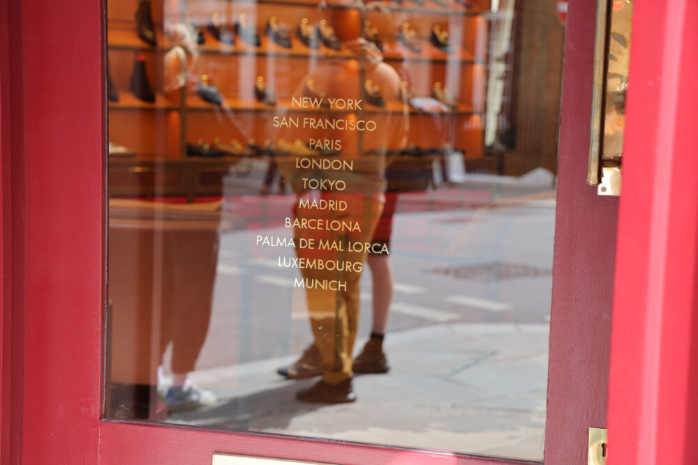 A glass door displays a list of city names including New York, Paris, and Tokyo, against a red frame.