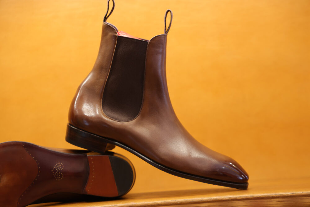 A polished brown leather Chelsea boot with elastic side panels and a stacked heel.