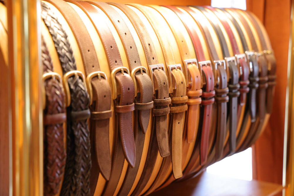 A collection of leather belts in various shades of brown and tan, some with woven designs and metal buckles.