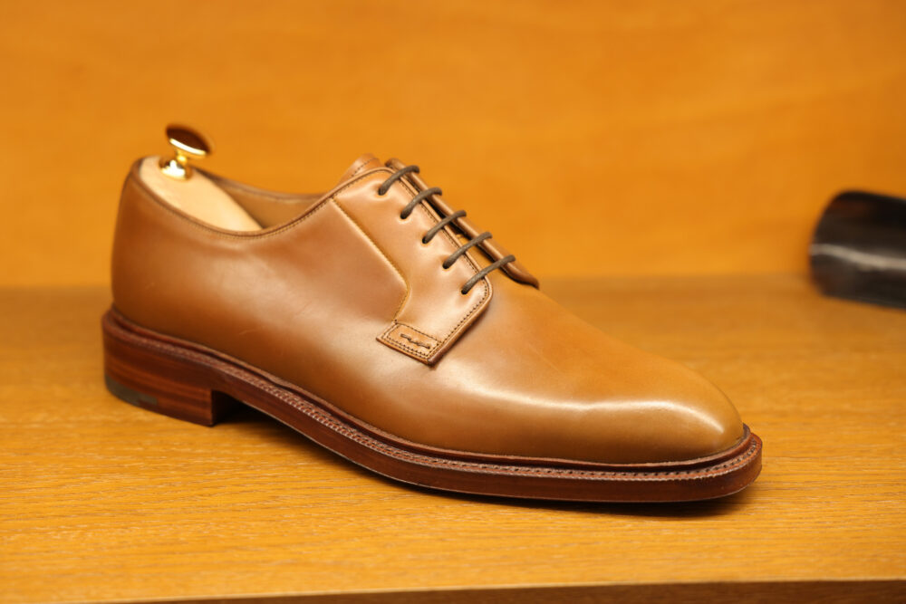 A polished brown leather dress shoe with a rounded toe and lace-up design.