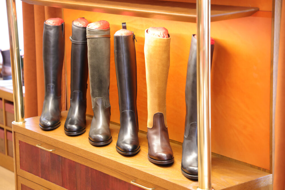 A display of six pairs of tall leather boots in various shades of black and brown.