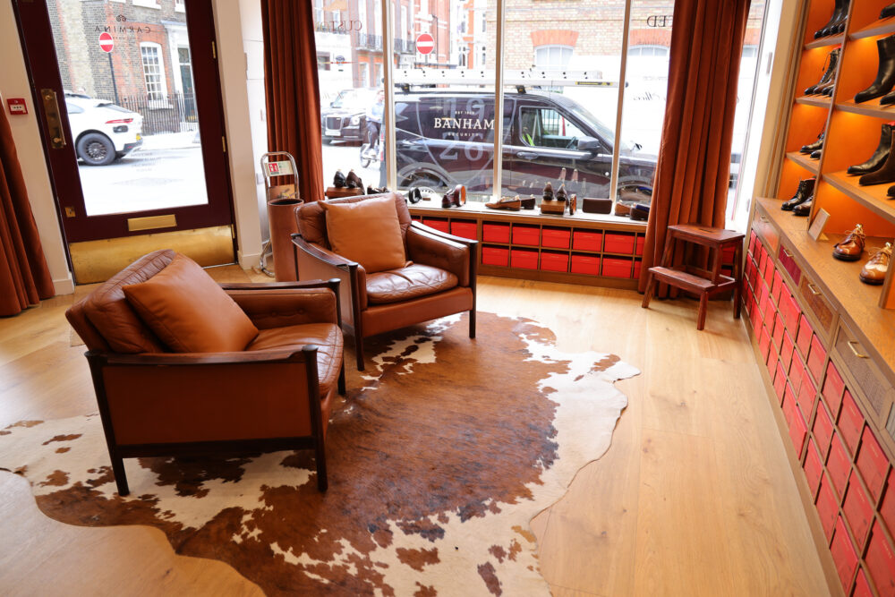 Two brown leather chairs on a cowhide rug in a shoe store.