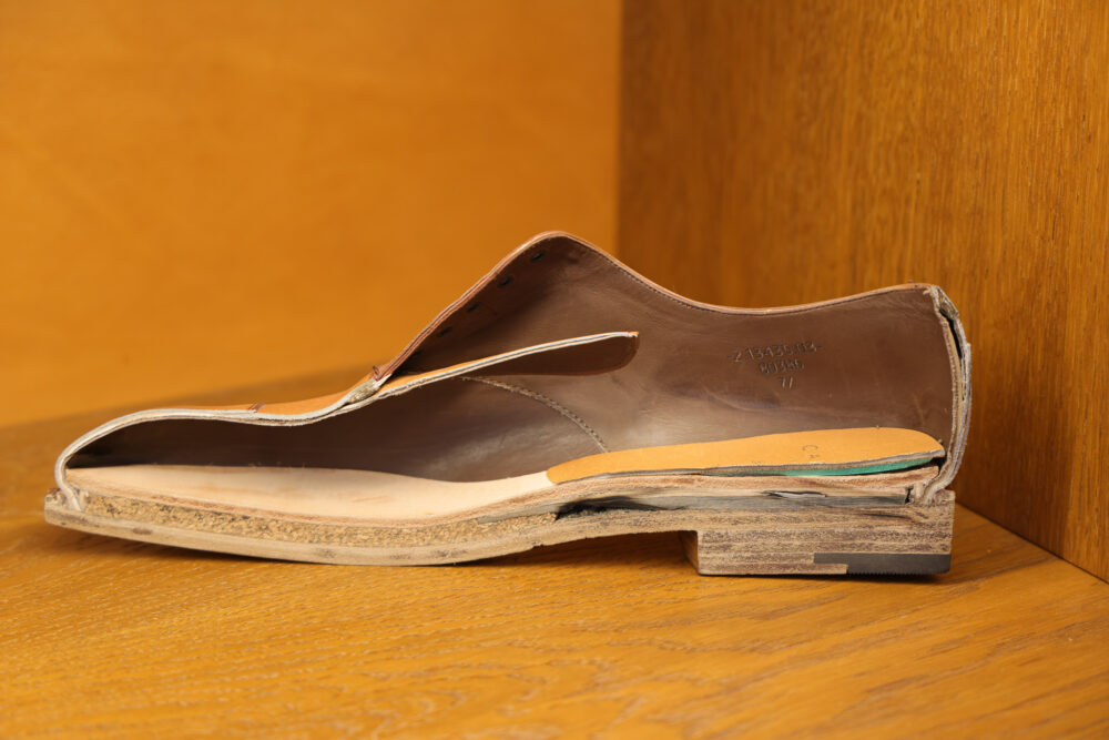 A cut-open leather shoe exposing its inner materials and cork sole.
