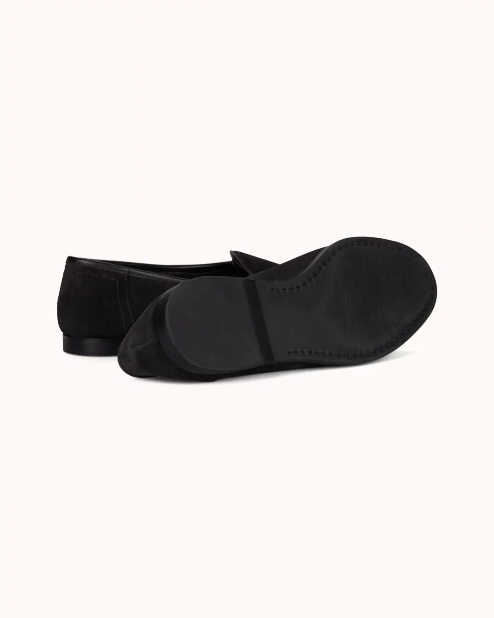 A pair of black suede flats with a smooth black sole.