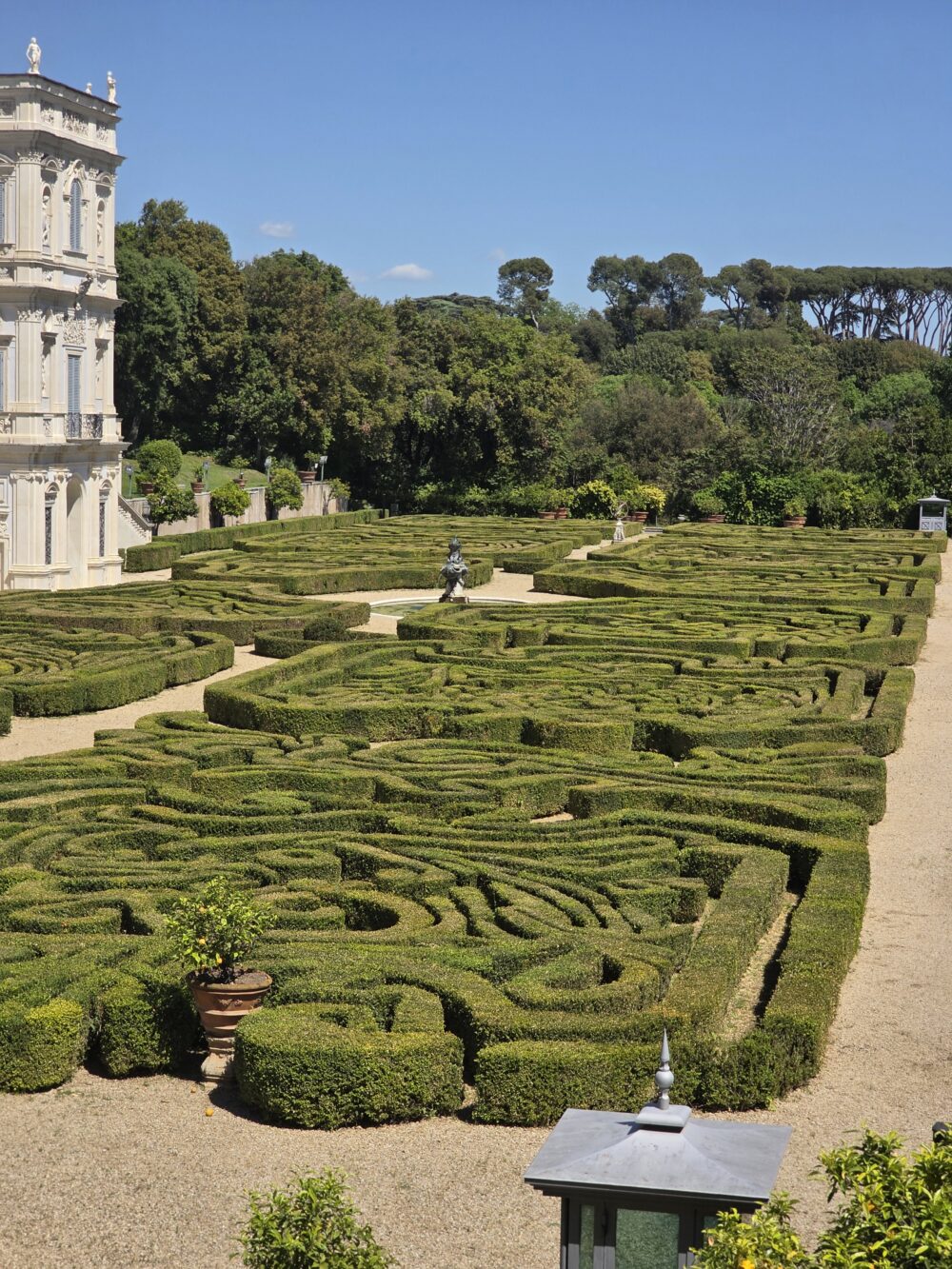 A neatly trimmed green hedge maze with a central decorative statue.