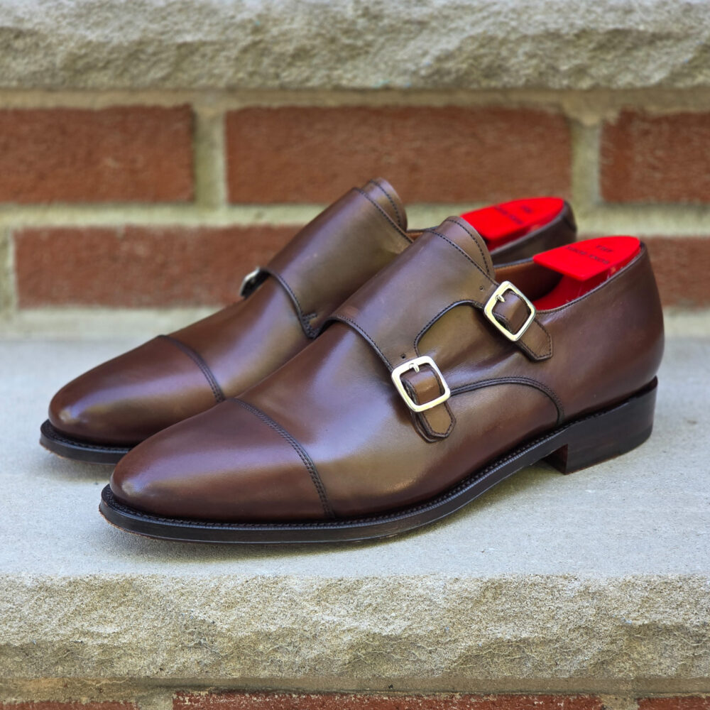 Brown leather shoes with two buckles and red insoles.